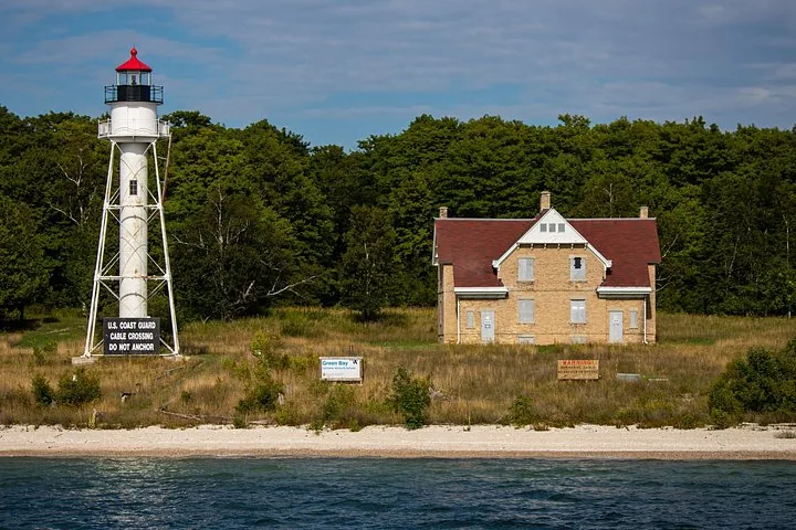 White lighthouse tower and brick keeper's house on a shoreline.