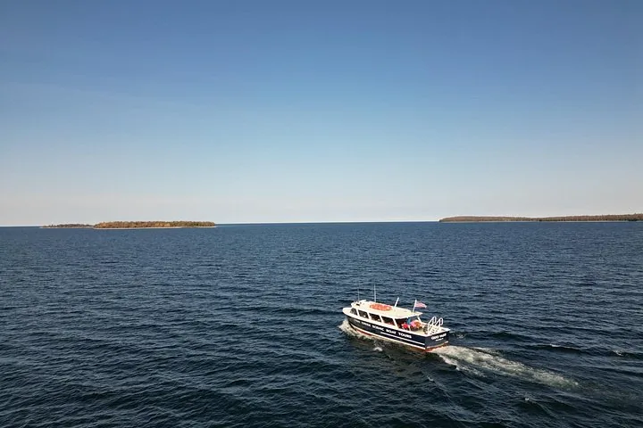 Een tourboot vaart over een groot blauw wateroppervlak.