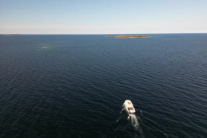 Una veduta aerea di una barca in acque aperte diretta verso un'isola.