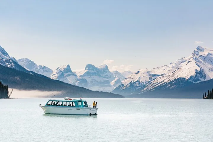 Ein Ausflugsboot auf einem ruhigen See, umgeben von schneebedeckten Berggipfeln